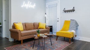 A living room with a brown sofa, yellow cushions, a small coffee table with a plant, and a yellow armchair. - New Lovely Lockhart Home with a Lawn (Lockhart)