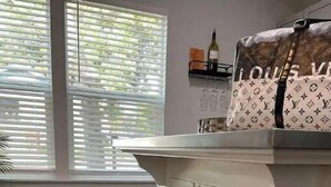 A kitchen with two wooden barstools, a white countertop, and a window with blinds. - New Lovely Lockhart Home with a Lawn (Lockhart)