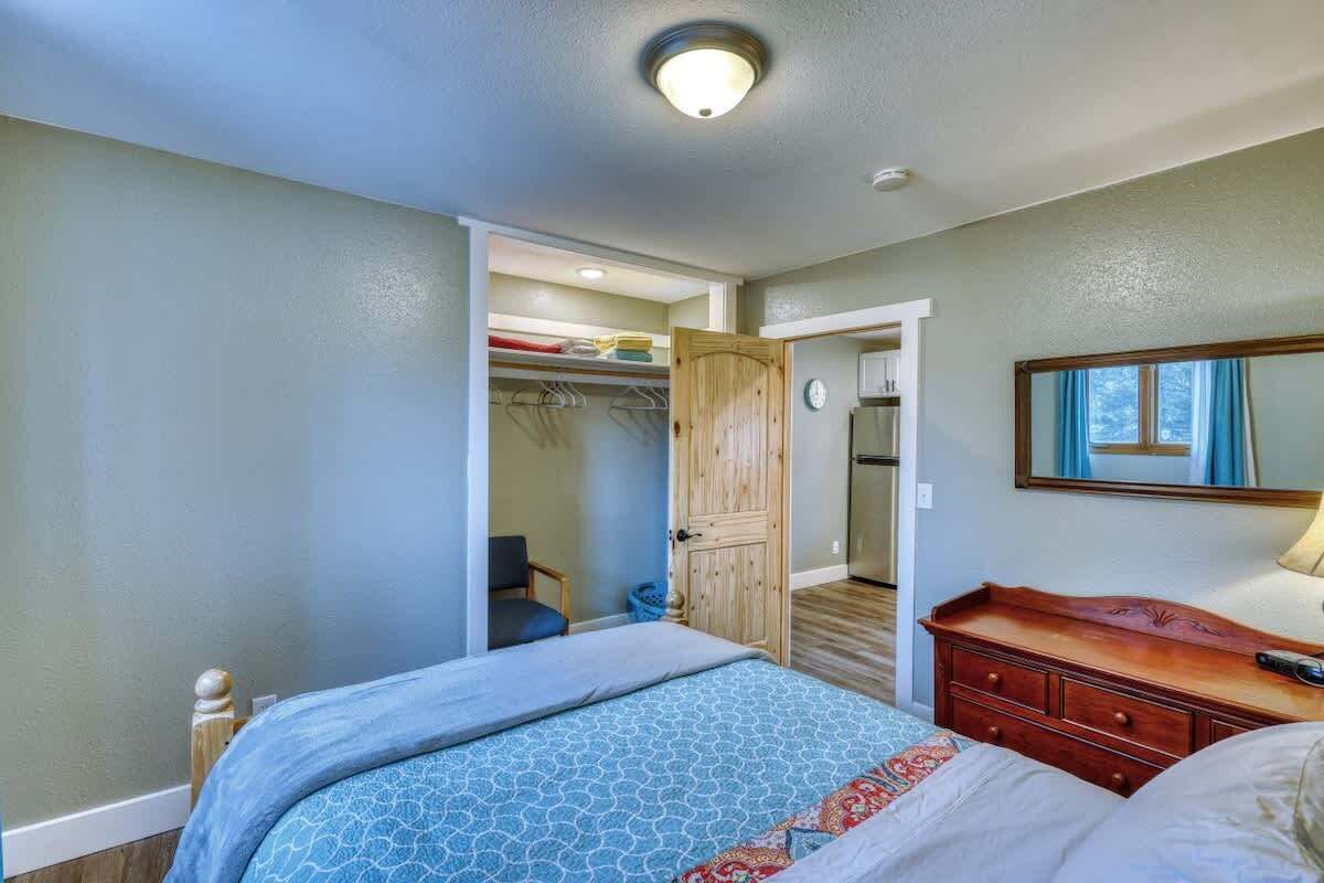 A bedroom with a bed, a dresser, a closet, and a door leading to a bathroom.