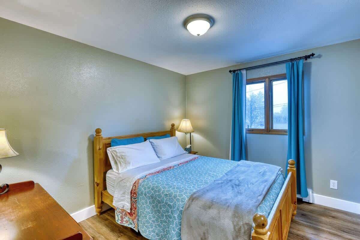 Una camera da letto con un letto di legno, una lampada da comodino e una finestra con tende.
