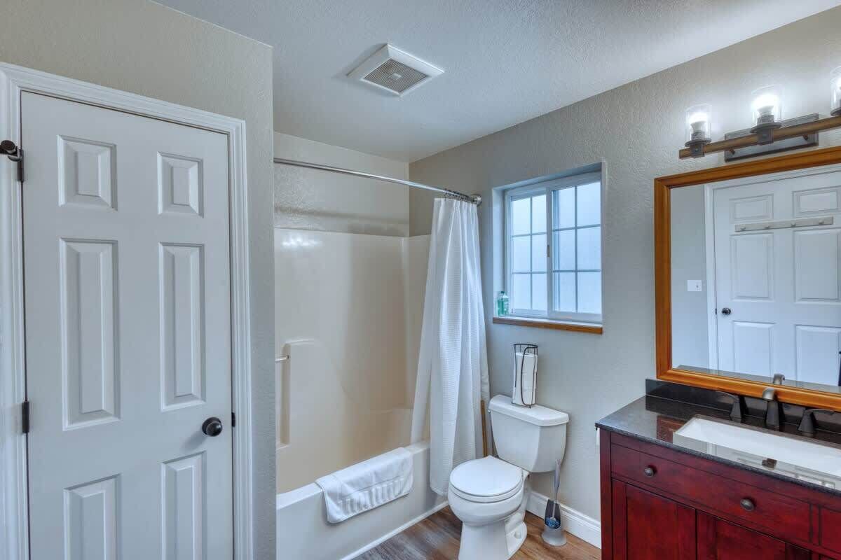 Een badkamer met douche, toilet, wastafel en een grote spiegel.