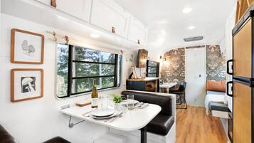 Un intérieur de camping-car compact comprenant un coin repas, un banc et un petit coin cuisine.