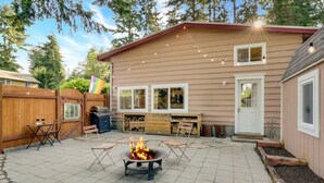 A backyard with a fire pit, outdoor seating, a barbecue grill, and a wooden deck. - Modern, Cozy Urban Homestead w/ Loft (Shoreline)