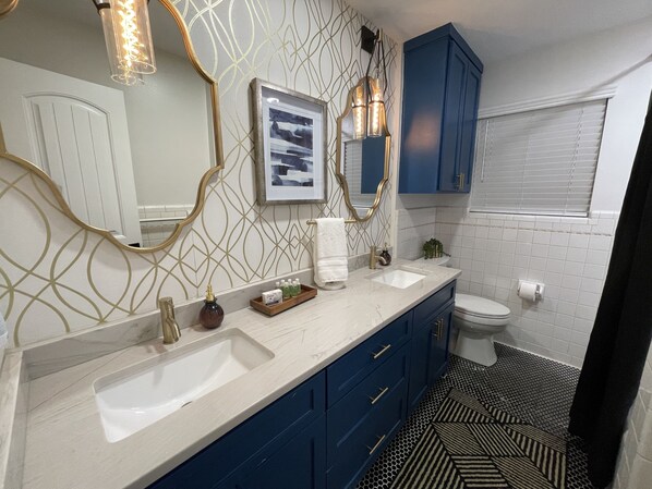 A bathroom with a white sink, blue cabinets, a toilet, and a patterned floor. - Stunning Remodeled Home, Minutes from Downtown (pet-friendly) (Dallas)