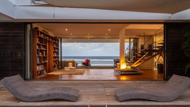 Una casa moderna con piscina, estanterías y vistas al océano.