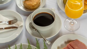 Et morgenbord med kaffe, kager og et glas appelsinjuice på et bord.