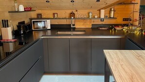 A modern kitchen with a central island, wooden ceiling, and built-in appliances. - PRESTIGE: RARE DUPLEX for 6 to 10 people (Saint-Sorlin-d'Arves)