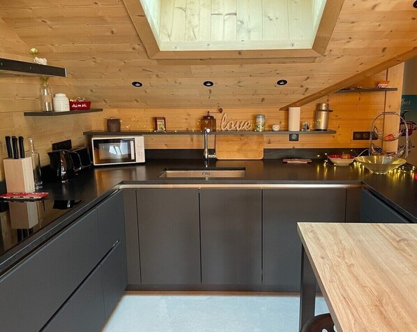 Una cocina moderna con una isla central, techo de madera y electrodomésticos integrados.