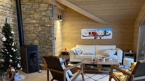 A cozy living room with a stone wall, a fireplace, a white sofa, and two wooden chairs. - PRESTIGE: RARE DUPLEX for 6 to 10 people (Saint-Sorlin-d'Arves)