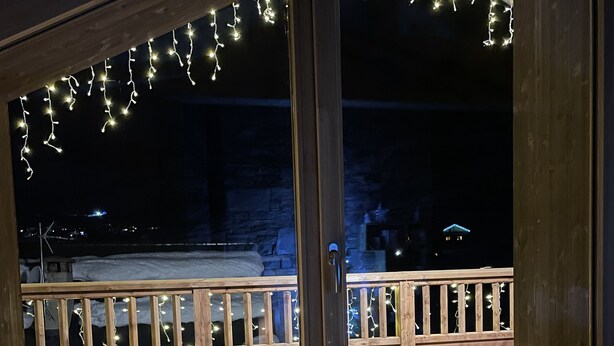 A wooden deck with a bench and a fluffy stool, overlooking a stone wall and a distant building. - PRESTIGE: RARE DUPLEX for 6 to 10 people (Saint-Sorlin-d'Arves)