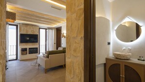 A modern living room with a fireplace, a sofa, and a television. - Alpujarras | Palatine Concept Suites | Luxury Apartments in Granada Center (Granada)
