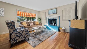 A living room with a sofa, armchair, coffee table, fireplace, and a television.