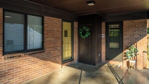 A brick building with a green door, a wreath, and a potted plant.