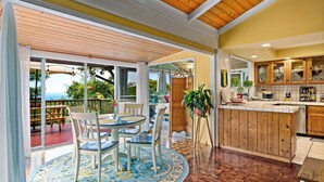 Une cuisine spacieuse avec des meubles en bois, un coin repas avec une table ronde et des chaises, et une vue sur l’extérieur.