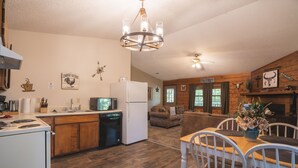 A kitchen with a refrigerator, microwave, and stove. There is a dining area with a table and chairs.