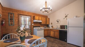 A kitchen with wooden cabinets, a white refrigerator, and a dining table with chairs.