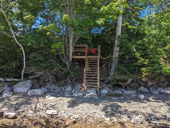 A wooden ladder leading to a platform surrounded by trees and rocks. - 2-Bedroom Cottage On Lake Ainlsie Private Beach, Enjoy Fishing & Swimming. (INVERNESS)