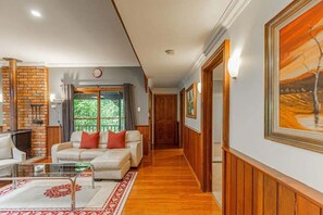 Una sala de estar acogedora con chimenea, un sofá con cojines, una mesita de centro y un cuadro grande en la pared.