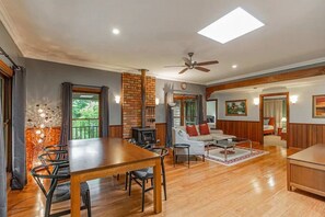 A spacious living area with a wooden dining table, a sofa, and a fireplace. - Tranquil 4 Bedroom Cottage in Olinda (Olinda)