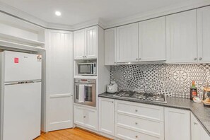 A kitchen with white cabinetry, a microwave, an oven, and a gas stove. - Tranquil 4 Bedroom Cottage in Olinda (Olinda)