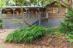 A wooden cabin with a covered porch and a staircase leading to a deck.