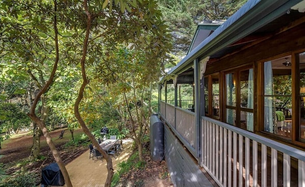 A covered outdoor area with a wooden deck, a grill, and a table with chairs. - Tranquil 4 Bedroom Cottage in Olinda (Olinda)