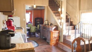A spacious living area with a wooden floor, a staircase, and a dining table. - Walking distance to French Quarter and Frenchmen Street with Pool!  (New Orleans)