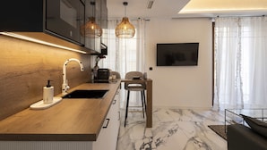 Une cuisine moderne dotée d’un plan de travail en bois, d’un évier encastré et de luminaires suspendus.