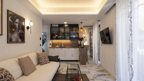 Un salon moderne avec un canapé, une table basse en verre et une cuisine en arrière-plan.