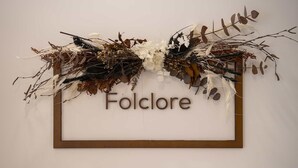 Une œuvre d’art encadrée, portant le mot « Folclore » et représentant divers éléments naturels, tels que des feuilles et des branches.