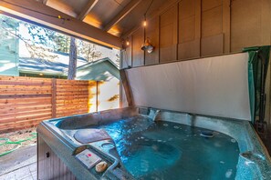 Een jacuzzi met bedieningspaneel, omgeven door houten wanden en een raam.