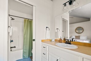 Een moderne badkamer met een douche, wastafel en spiegel.