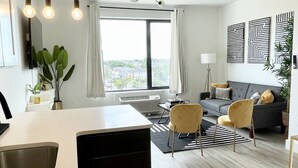 Una sala de estar moderna con un sofá, sillas, un comedor y un ventanal con cortinas.