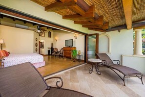 A spacious room with a bed, a desk, a TV, and a lounge area with a chair and a table. - Palms 23 (The Palms)
