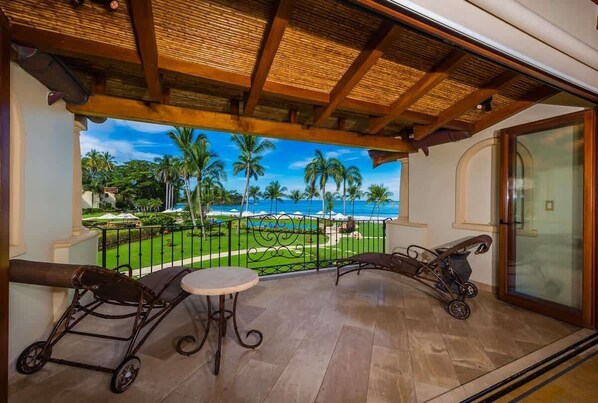 Un balcon offrant une vue sur un paysage tropical, avec des palmiers et une plage.