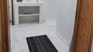 Casa de banho moderna com toucador branco, soalho em mármore, tapete preto e arte decorativa nas paredes.