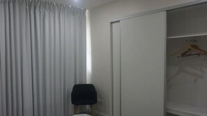 Quarto com armário grande, uma cadeira e cabideiro.