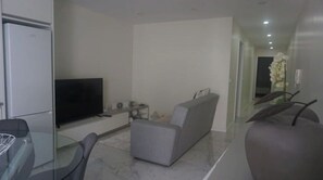 A modern living room with a flat-screen TV, grey sofa, and a glass dining table with chairs. - Apartment in the historic center of Ponta Delgada (Ponta Delgada)