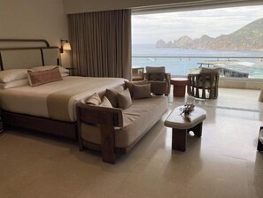Relax in comfort with a large bed and sofa, perfect for unwinding with a view of the sea and distant rocky formations.