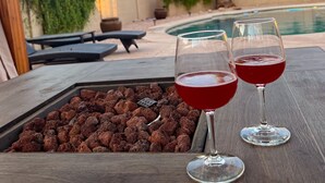 Una mesa de madera con dos vasos de un brebaje rojo y una bandeja de piedras de chocolate.