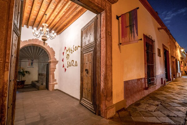 Un edificio histórico con una puerta de madera grande, un candelabro y un letrero que dice "Meson Garcia".