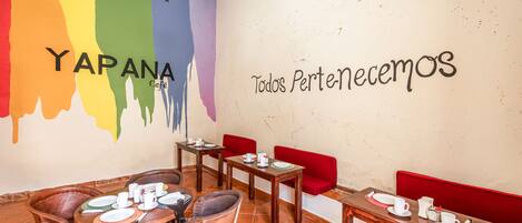 A restaurant interior with a colorful wall mural, wooden furniture, and a clean, well-lit space.