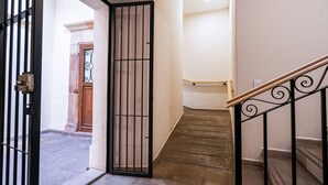 A staircase with a wooden handrail and black metal balusters, leading to an upper floor. - Hotel Mesón de Sara (Querétaro)