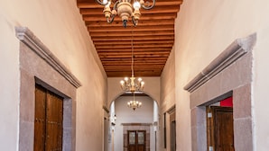 A corridor with a wooden ceiling, stone walls, and a chandelier. - Hotel Mesón de Sara (Querétaro)
