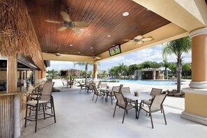An outdoor bar area with seating, a pool, and a TV screen. - New Listing! Paradise Palms Resort, 6mi to Disney & 14mi to Universal - GRH509175 (Kissimmee)