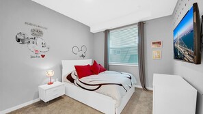 A bedroom with a bed, a nightstand, a lamp, a dresser, and a large window with blinds. - New Listing! Storey Lake Resort, 6mi to Disney & 11mi to Universal - GRH520205 (Kissimmee)