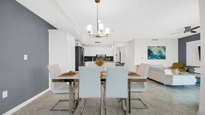 A modern dining area with a chandelier, white dining chairs, and a central table. - New Listing! Storey Lake Resort, 6mi to Disney & 11mi to Universal - GRH520205 (Kissimmee)