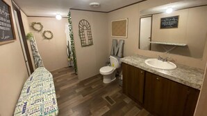 Un baño con suelo de madera, inodoro, lavabo y espejo.