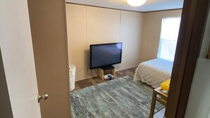 Una habitación pequeña con televisión, cama y una alfombra.