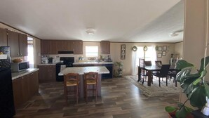 Una cocina amplia con armarios de madera, una isla central y una zona de comedor con mesa y sillas.